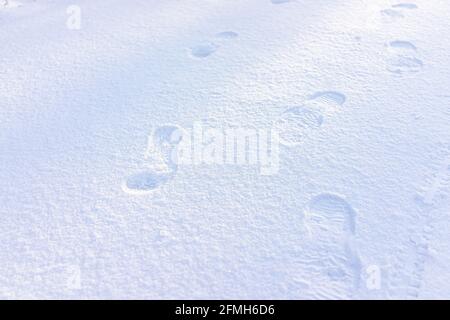 Blue driveway road street with snow covered ground from white storm in Virginia suburbs with footprints closeup shining glittering from sunlight Stock Photo