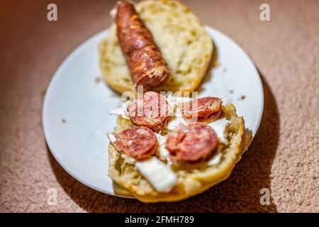 Macro closeup of Spanish salchichon salami sausage sliced on bread toast with butter as snack on plate Stock Photo