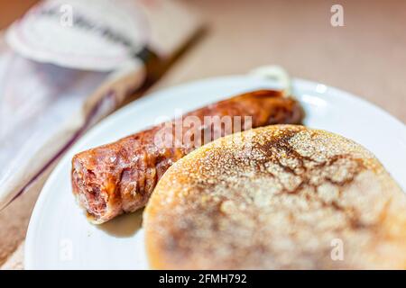 Macro closeup of Spanish salchichon salami sausage and english muffin bread toast with meat as snack on plate with package in background Stock Photo