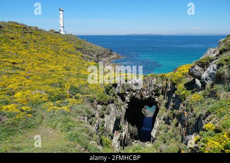 Atlantic coast gorse in flower with natural arch and a lighthouse in background, Galicia, Spain, Pontevedra province, Cangas, Cabo Home Stock Photo