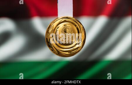 April 25, 2021 Tokyo, Japan. Gold medal of the XXXII Summer Olympic Games 2020 in Tokyo on the background of the flag of Hungary. Stock Photo