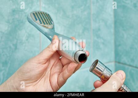 Clogged shower head is detached from flexible hose to be replaced with new one. Stock Photo
