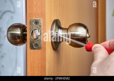 Joiner uses screwdriver to secure both handle sides to door. Stock Photo