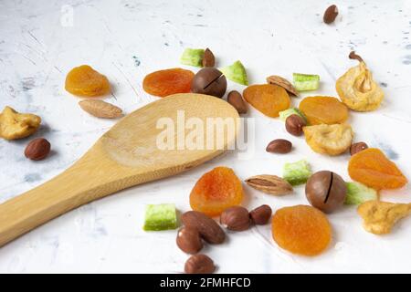 Dried fruits and nuts, apricot, almond, hazelnut pear prune and macadamia with bamboo wooden spoon on white background. Stock Photo