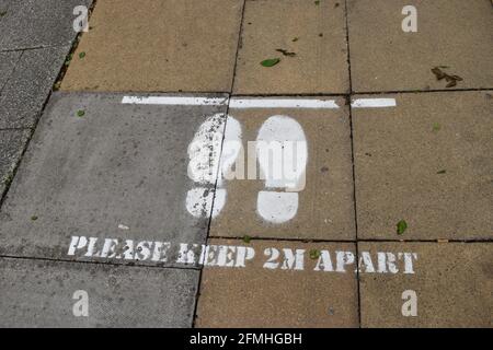 Social distancing notice on pavement: Please keep 2m apart. Stock Photo