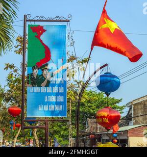 Vietnam flag and propaganda poster hanging in street of Hoi An, Vietnam Stock Photo