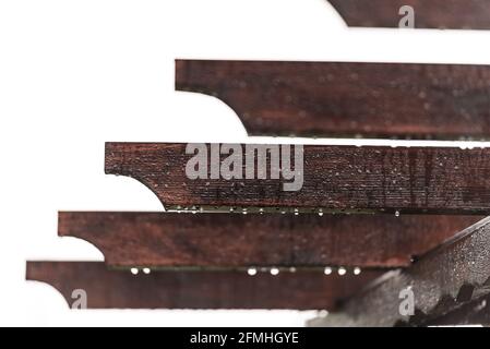 Pergola roof close-up. Individual elements of a wooden roof with raindrops. Brown beams and water droplets hanging down. Stock Photo