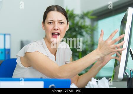 frustrated woman shouting and gesturing at her computer Stock Photo
