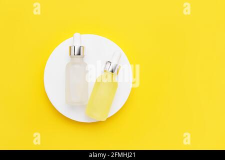 Two glass dropper bottles for medical and cosmetic use on a bright yellow background. SPA concept. Top view, copy space Stock Photo
