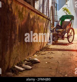 Vietnamese cyclo sits outside dwelling at end of dark alleyway, Hoi An, Vietnam Stock Photo