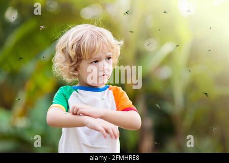 Mosquito on kids skin. Little boy attacked by mosquitoes in tropical forest. Insect repellent. Malaria and dengue fever prevention. Stock Photo