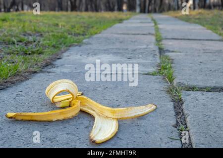 a carelessly discarded banana peel in the form of garbage lies on a concrete footpath on the way to the city park Stock Photo
