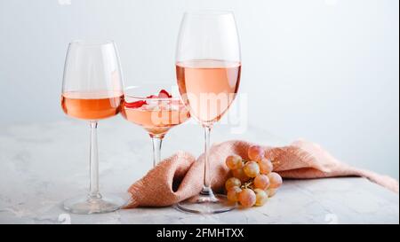 Rose wine in different types of glasses on light grey concrete background with grapes. Rose Wine composition on white table. Long web banner with copy Stock Photo