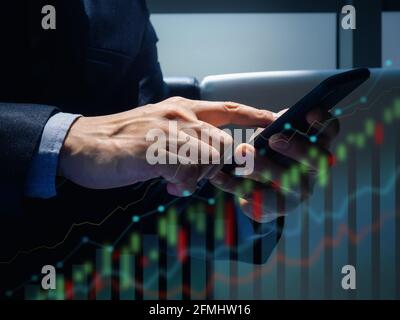 Stock trading market business concept. Smartphone in hands. Close-up finger of a businessman in suit checking financial statistics with chart graph on Stock Photo