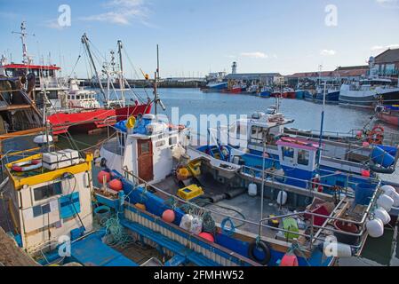 Landscape panorama view of coastal seaside town harbor port with fishing boats moored up on dock Stock Photo