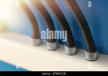 The electrical wires in the corrugated protection are attached to the cable duct by means of nuts. Industrial background with backlighting and copy space. Stock Photo