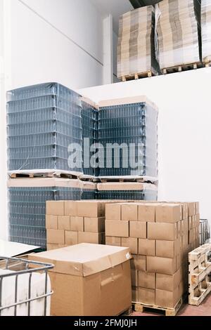 Warehouse with heaps of carton boxes and plastic containers with bottles of beer in factory Stock Photo