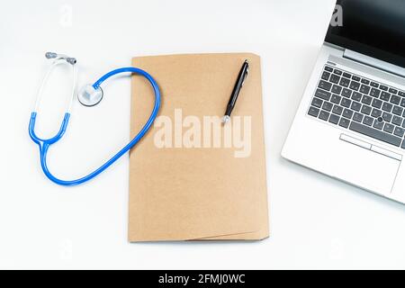 From above modern medical workspace with laptop, stethoscope and paper form document on folder on desk in hospital Stock Photo