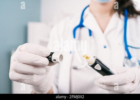 Crop unrecognizable female nurse in sterile gloves with blood sampling device at work in hospital Stock Photo