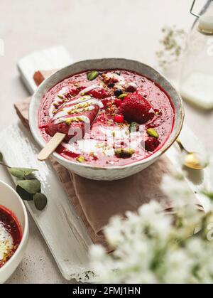 From above of tasty smoothie with fresh berries and ice candy with crushed pistachios and yogurt in bowl Stock Photo