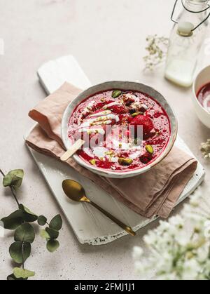 From above of tasty smoothie with fresh berries and ice candy with crushed pistachios and yogurt in bowl Stock Photo