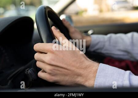Side view of crop faceless male with hands on steering wheel driving contemporary car Stock Photo