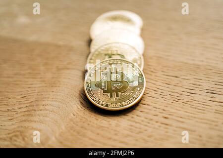 Row of similar metal crypto coins with letter on desk on shiny blurred background Stock Photo