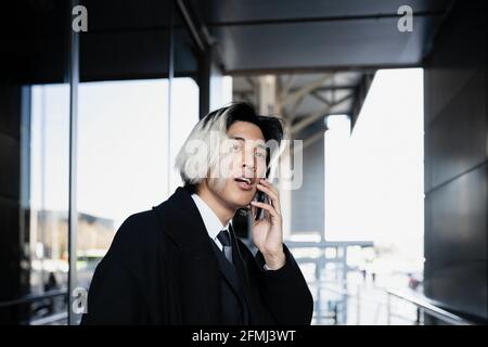 Young attentive Asian male executive in formal apparel on a phone call on a smartphone in daylight Stock Photo