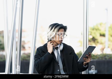 Young ethnic male entrepreneur in modern headphones and eyewear with tablet in town Stock Photo