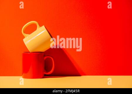 Creative colorful mugs on yellow and red background in studio Stock Photo