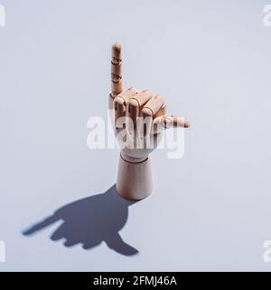 From above of decorative flexible wooden mannequin hand showing shaka sign placed on white background Stock Photo