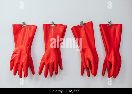 Composition of red rubber gloves hanging on clothes pins on white background in studio Stock Photo