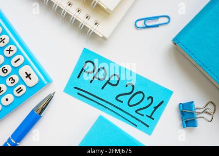 PPP loan 2021 handwritten words on a blue piece of paper. Stock Photo