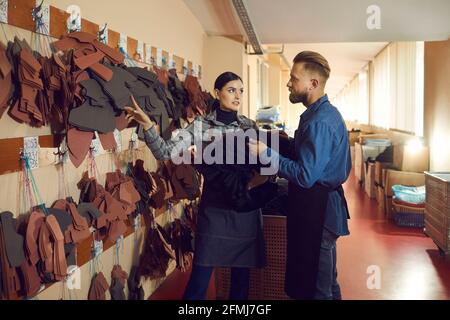 Male and female shoemaker colleague discussing shoes material choice on stand Stock Photo