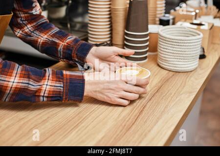 male waiter in apron holding cup of hot drink Stock Photo