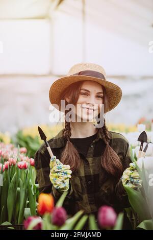 A woman takes care of tulips flowers in the garden. Spring and summer. happy woman gardener with flowers. Greenhouse flowers. Real professional. Soft Stock Photo