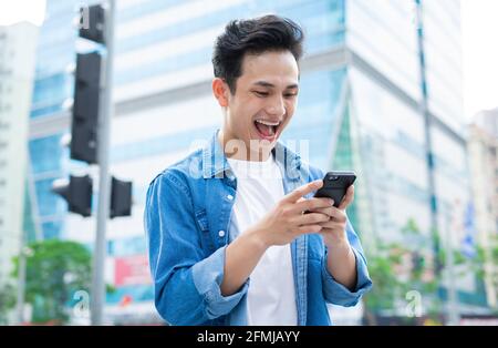 Young Asian man using smartphone while walking on the street Stock Photo