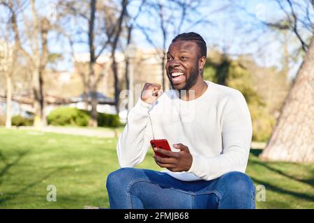 African American man celebrating good news by looking at his cell phone. Concept of happiness. High quality photo Stock Photo