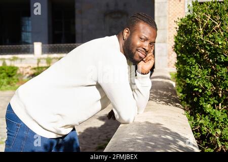 Young African American man smiling leaning against a wall, Happy Latino man. High quality photo Stock Photo