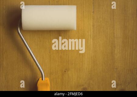 Close up shot of a paint roller on a wooden background. Stock Photo