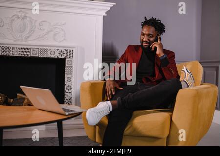 Smiling millennial african american casual man working with apps or communicating online on laptop Stock Photo