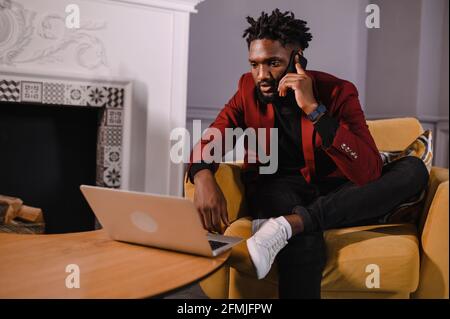 Smiling millennial african american casual man working with apps or communicating online on laptop Stock Photo