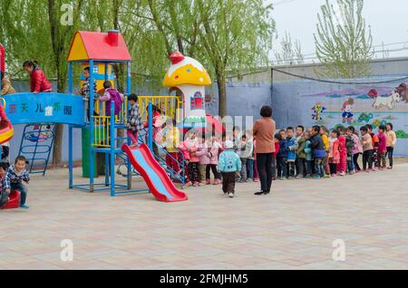 Kindergarten students line up patiently for their turn on the play structure at Lixian school in Hebei, China. Stock Photo