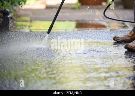 Cleaning patio paving with a high pressure washer the man is using the water to clean the garden path Stock Photo