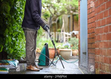 Cleaning patio paving with a high pressure washer the man is using the water to clean the garden path Stock Photo