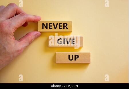 Never give up symbol. Wooden blocks with words 'Never give up'. Beautiful white background. Businessman hand. Copy space. Motivational, business and N Stock Photo