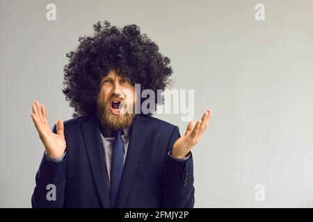 Funny man in afro hair wig angry shouting and gesturing at camera studio shot Stock Photo