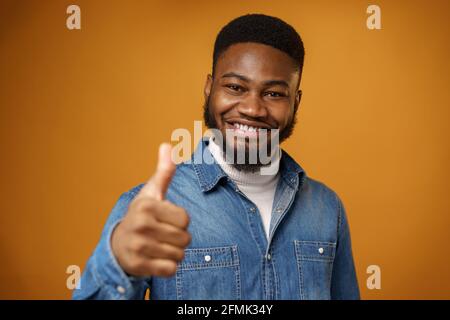 Happy smiling african american man showing thumb up, yellow background Stock Photo