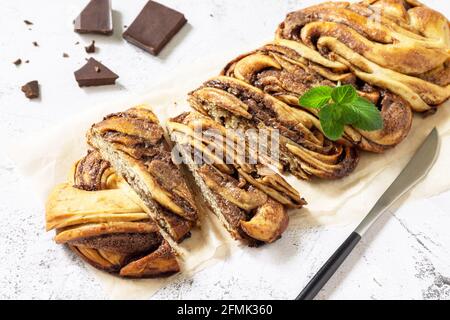 Fresh pastries, chocolate day. Chocolate babka or brioche bread. Sweet yeast dough with chocolate filling and accompanied and nuts. Stock Photo