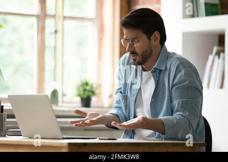 Unhappy irritated businessman in glasses looking at laptop screen Stock Photo